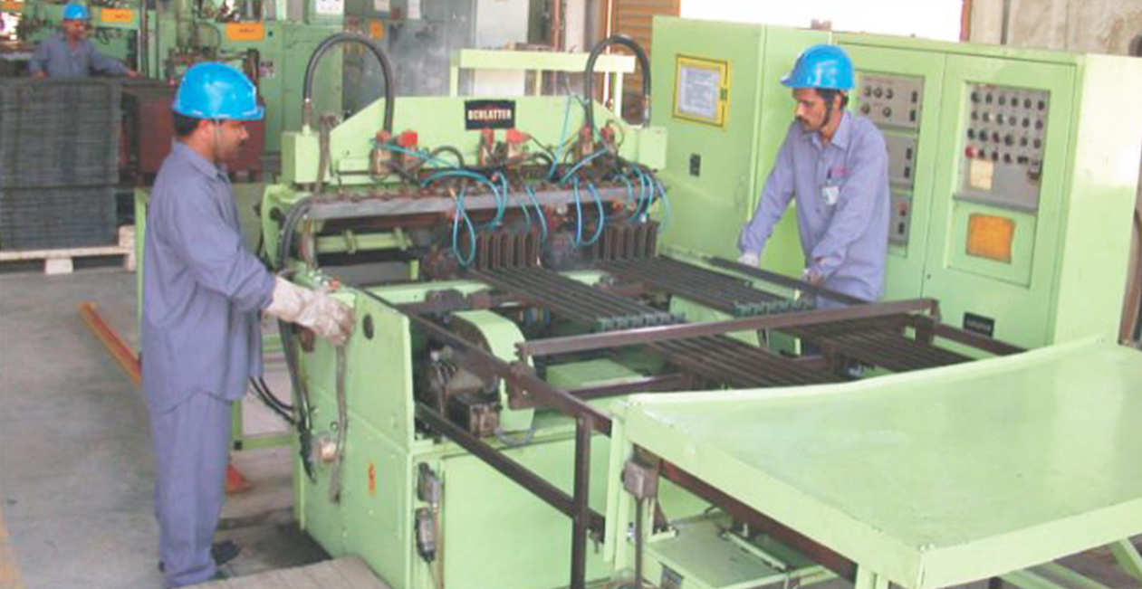 Operators managing industrial CNC welding machines for automated component joining