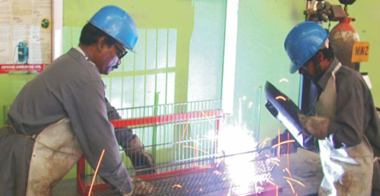 Workers performing MIG welding process with protective gear in industrial workshop